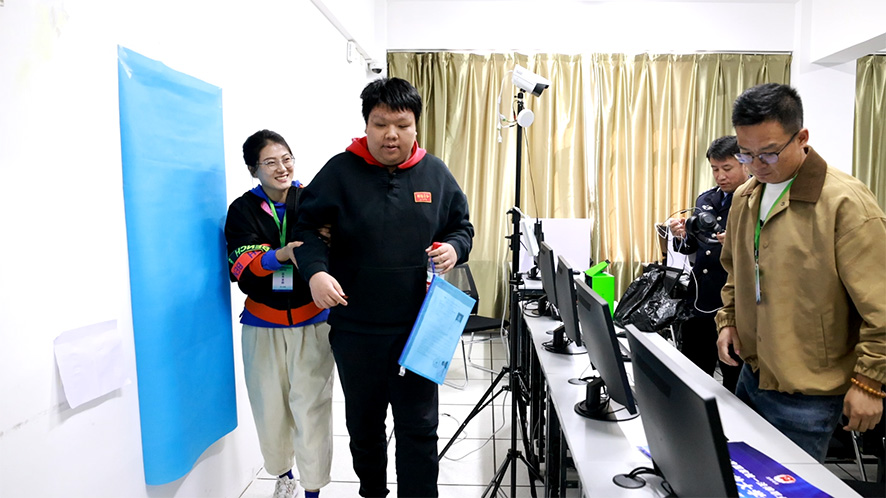 遼寧開放大學考區(qū)考務人員幫助盲人考生參加考試。